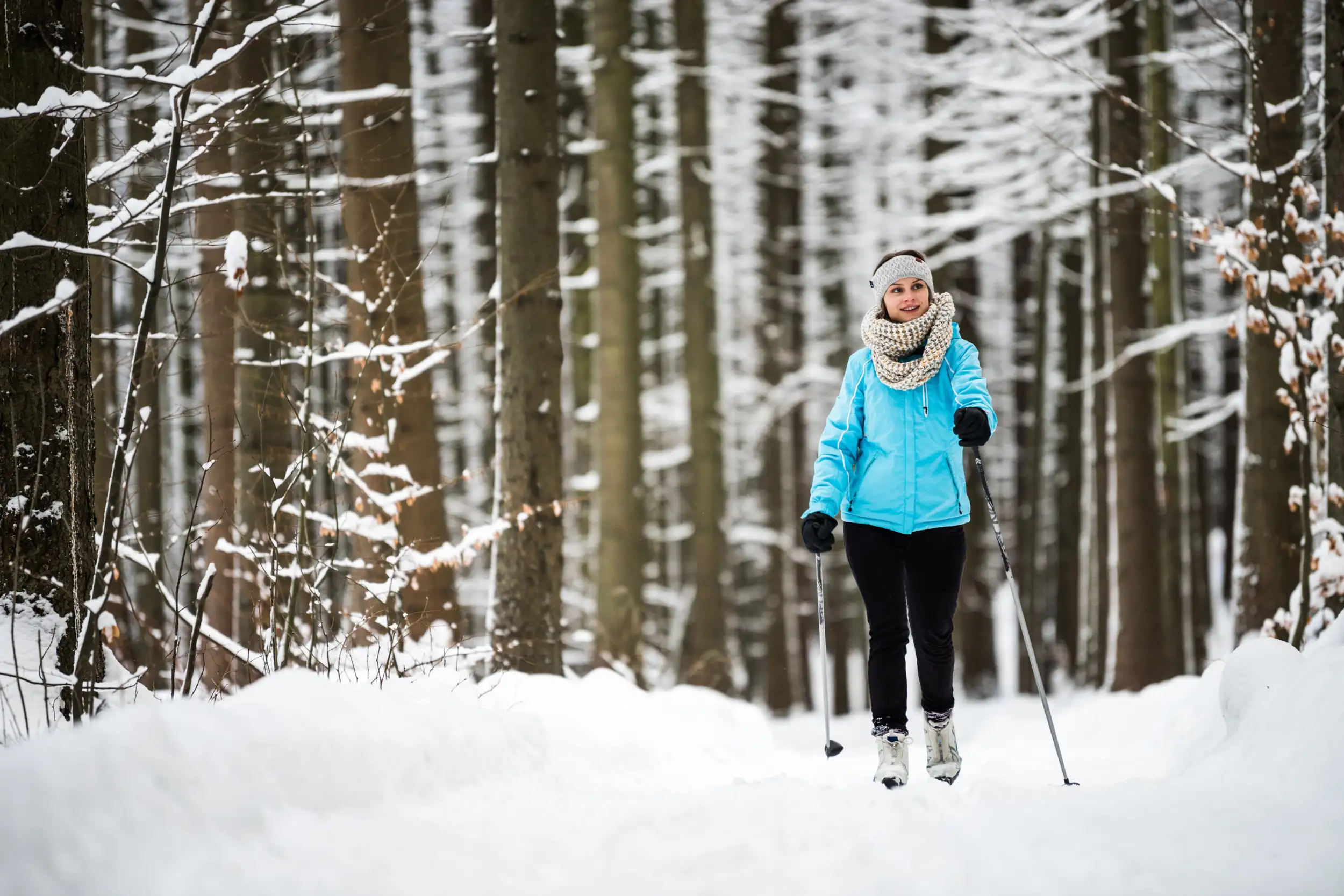 Eine fröhliche Langläuferin ist im verschneiten winterlichen Wald bei Sebnitz unterwegs.