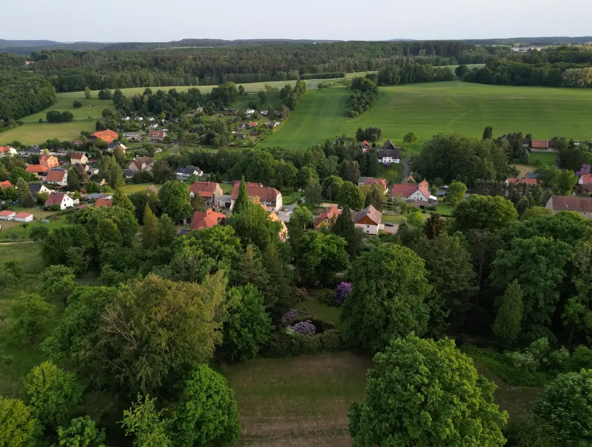 Ein kleines Dorf mit roten Dächern liegt eingebettet zwischen den markanten Sandsteinfelsen der Sächsischen Schweiz.