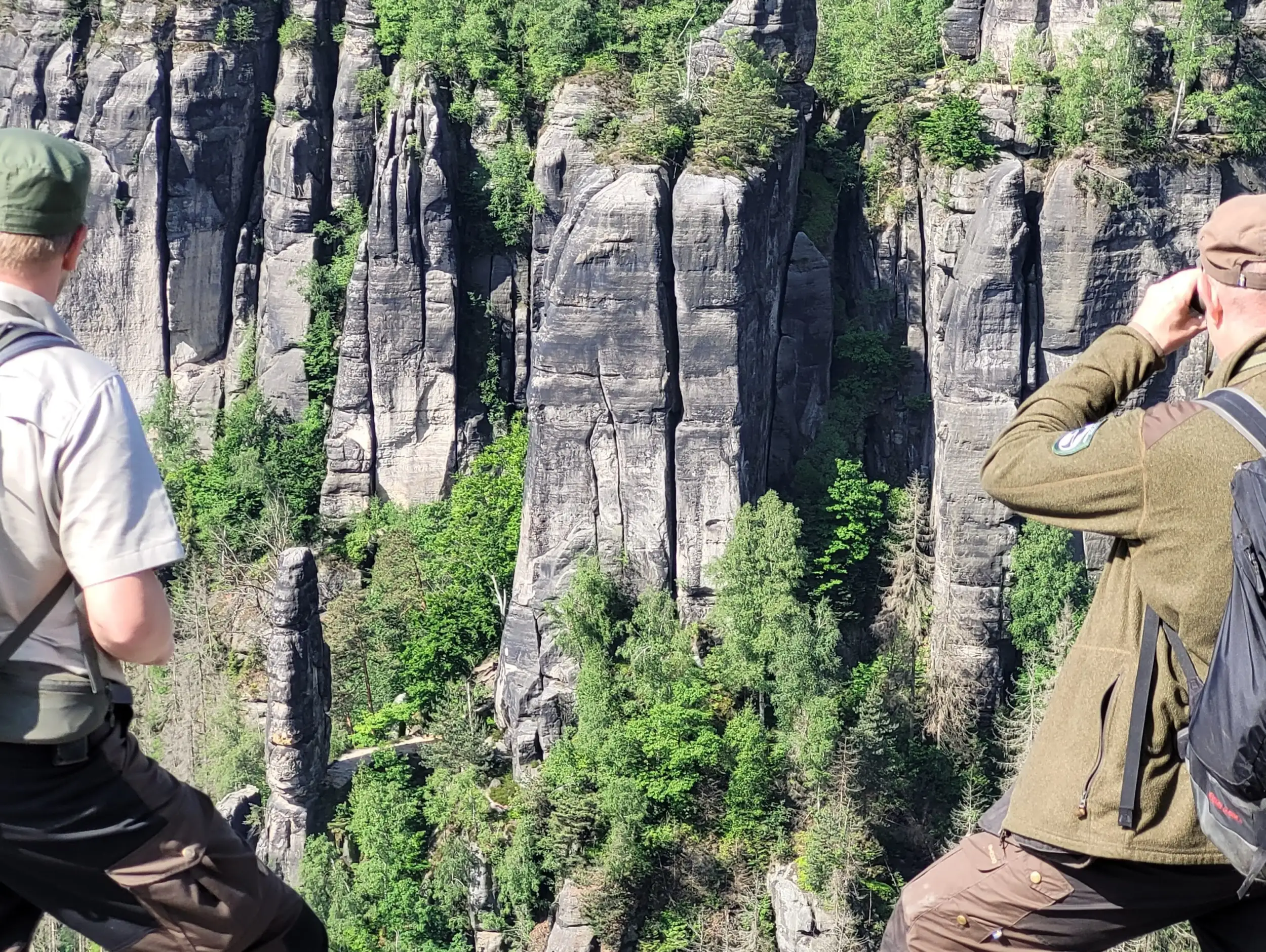 Zwei Ranger mit Fernglas beobachten die Tier und Pflanzenwelt in den Felsen