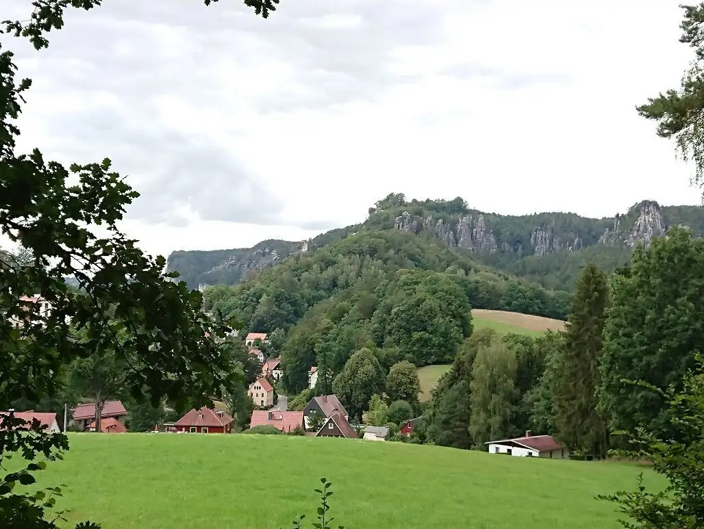 Ein Dorf liegt malerisch zwischen Wiese und bewaldtenten Bergen