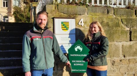 Christian Starke übergibt mit einem Nationalparkschild symbolisch die Leitung für den Fachbereich Naturschutz, Gebietsentwicklung und Forschung an Astrid Scharf. Sie arbeitete bereits acht Monate in diesem Bereich, bevor sie nun die Leitung übernahm. Starke ist seit vergangenem Jahr Leiter des Wildnisgebiets auf dem ehemaligen Truppenübungsplatz Königsbrück. Foto: H. Mayr